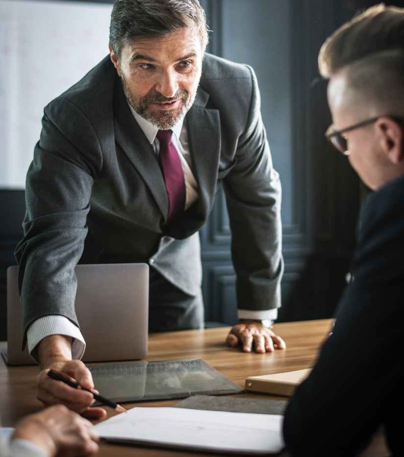 man holding pen pointing note in front of man in black suit